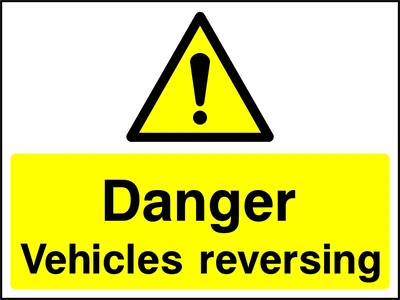 A black exclamation mark inside a yellow warning triangle above black wording on a yellow panel with Danger — Vehicles reversing wording. CONS0097 artwork.